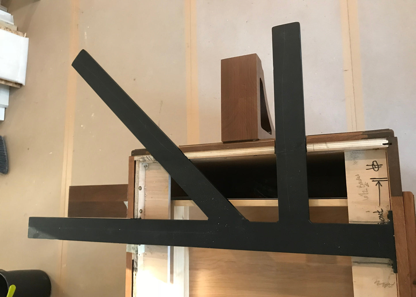 A Black Custom Support Bracket in a ‘K’ shape on a dark brown wooden countertop.