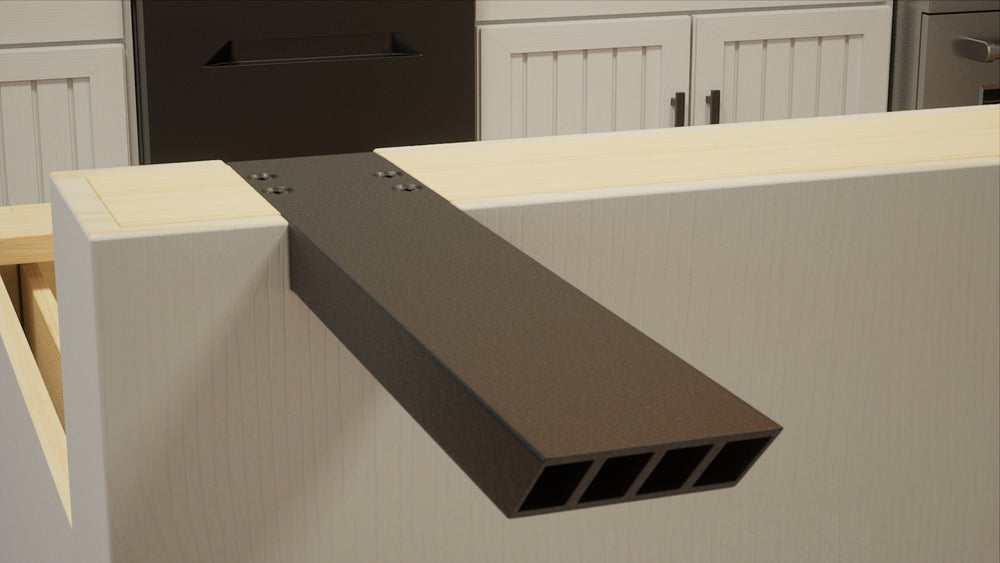 
                  
                    A close-up left-angle view of an Industrial L Countertop Support Bracket secured to a beige kitchen island with white cabinets and stainless steel appliances in the background.
                  
                